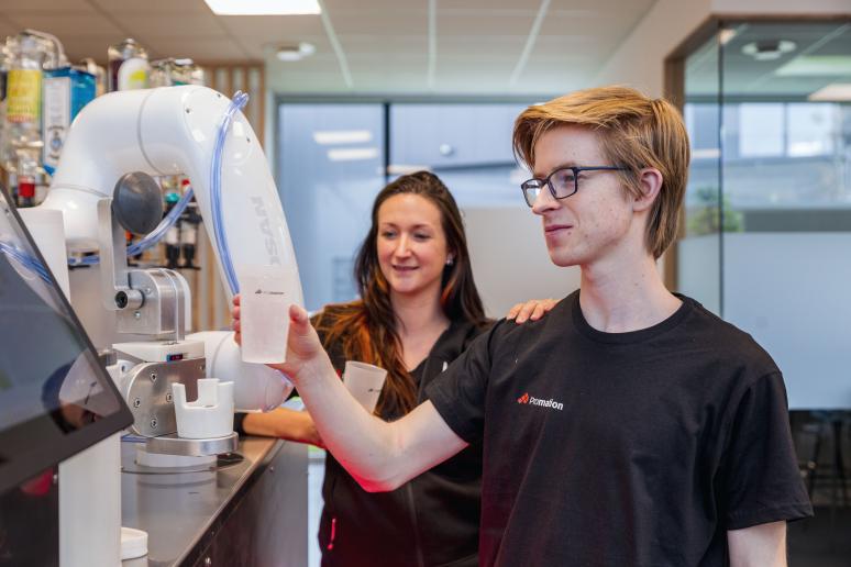 Un homme avec un verre devant le robot Cotender